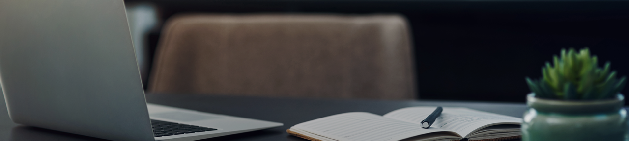 Laptop on Desk with Notebook and Pen