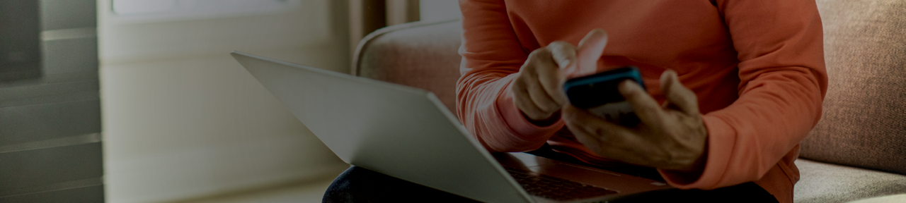 Person Using Phone and Laptop to Browse Savings Accounts