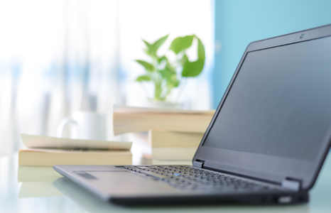 Open Laptop Beside Stack on Books on Desk 