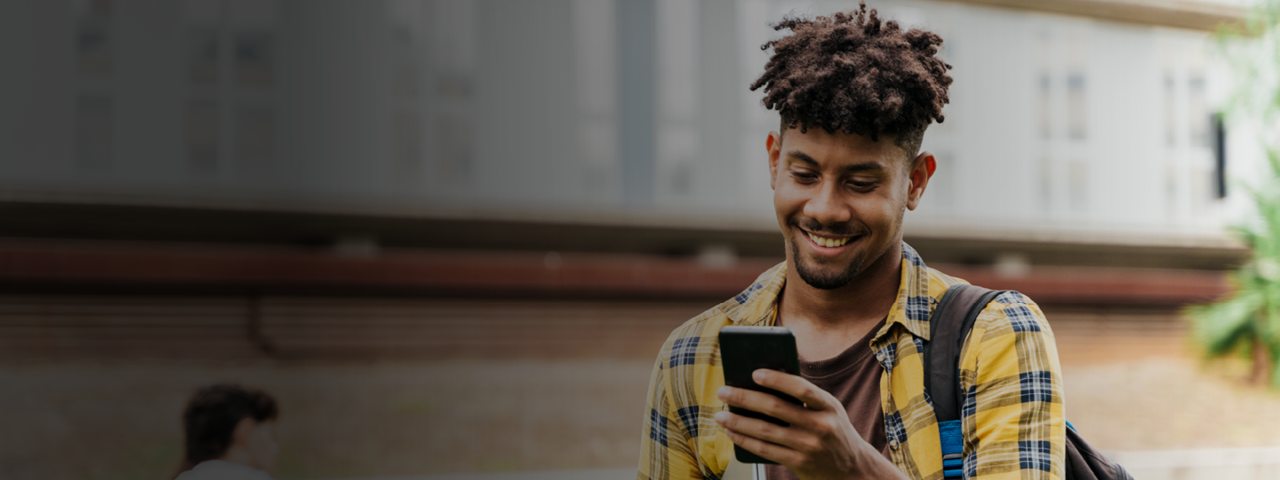 Young Man Smiling While Using Mobile Phone
