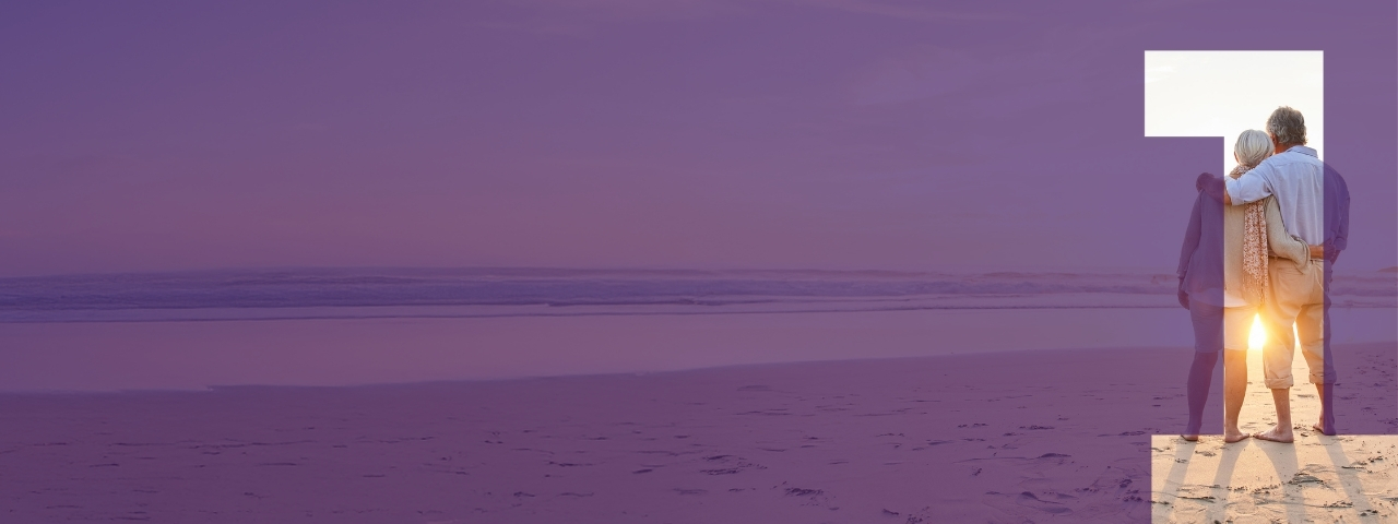 Couple standing on the beach at sunset