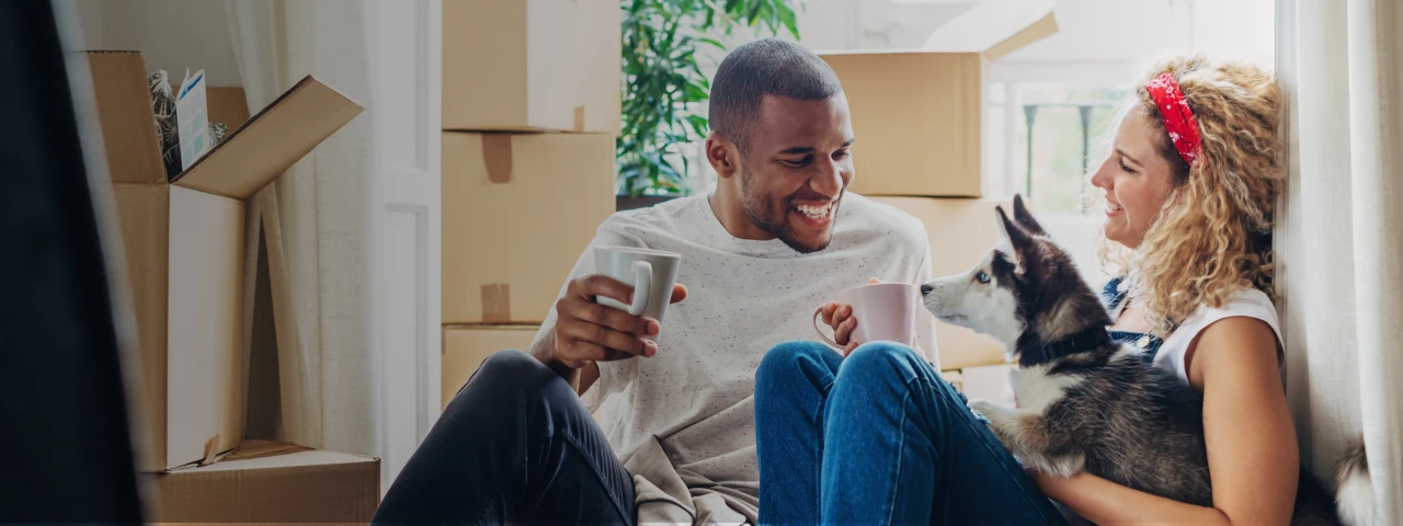 Smiling couple and Dog Sitting Amongst Moving Boxes