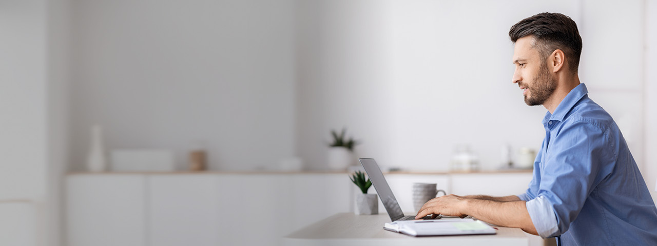 Man in blue collared shirt working on laptop