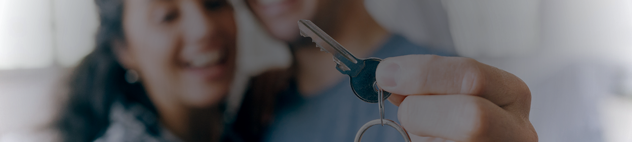 Couple Holding Key to New House and Smiling