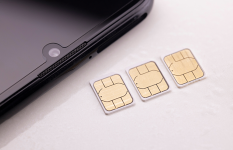 Three SIM cards beside smartphone