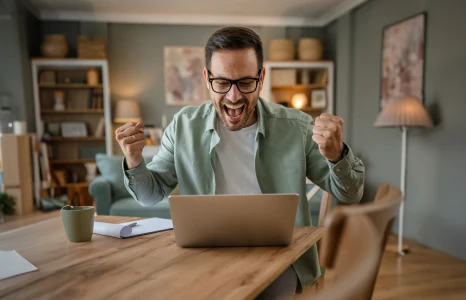 Man celebrating while opening a new chequing plan on laptop