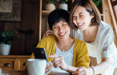 Mother and daughter smiling while looking at dividend returns from Investment shares