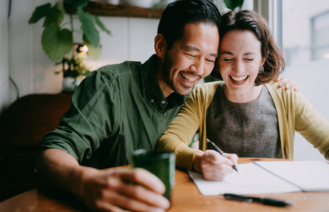 Couple Smiling While Signing Documents