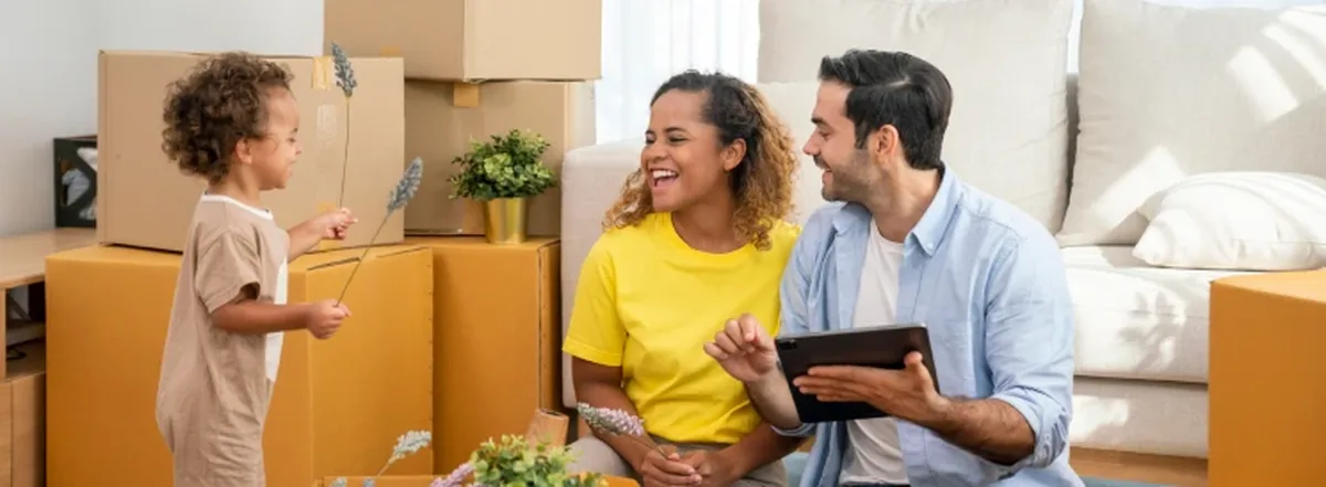 Young family sitting on floor of new home with moving boxes