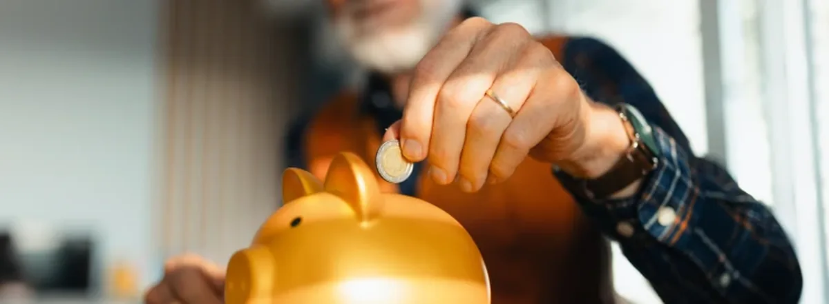 Man putting coin into gold piggy bank