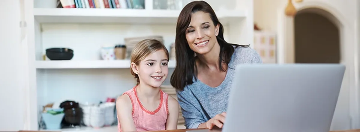 Mother and daughter sitting at laptop together
