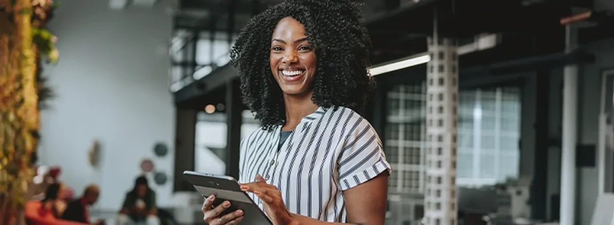 Woman smiling while holding tablet in office