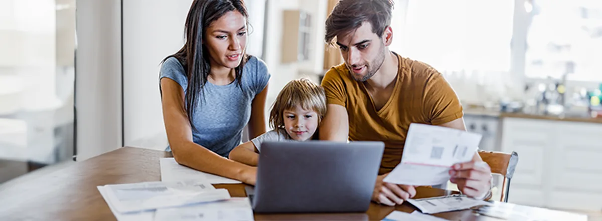 Family of three sitting at kitchen table with paper work
