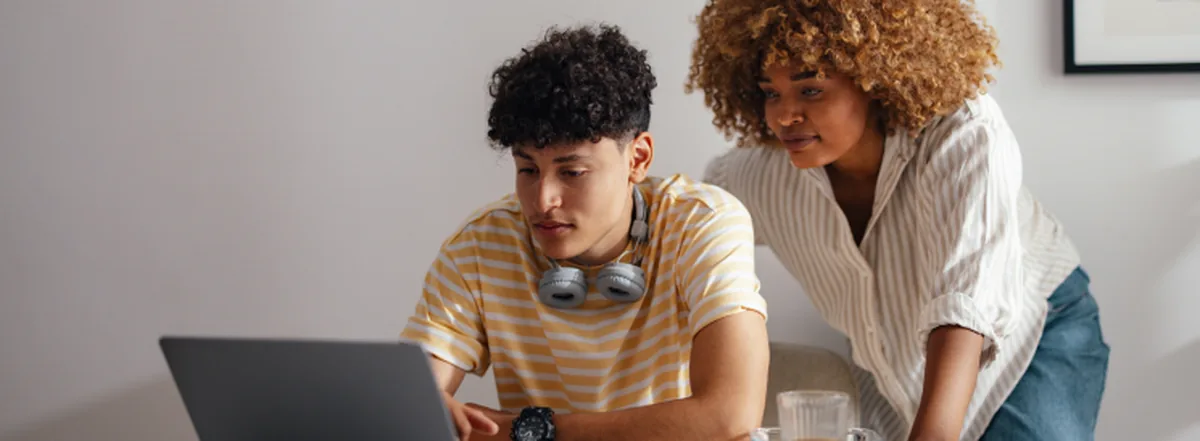 Mother and teenage son researching savings options on laptop
