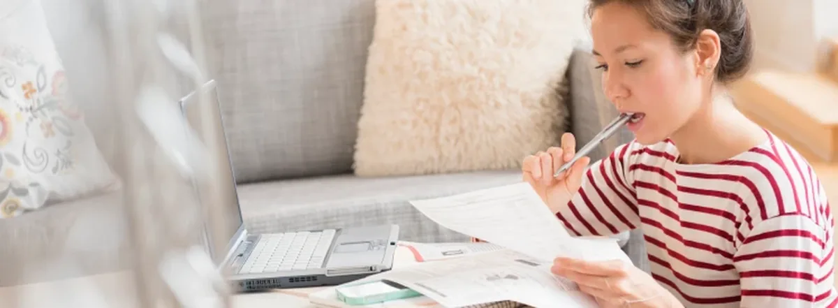 Woman reviewing her finances on couch with laptop