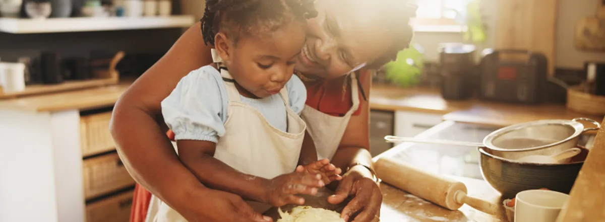 Retired woman and grandchild baking in sunny kitchen