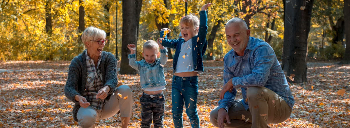Grandparents playing in the fall leaves with two grandchildren