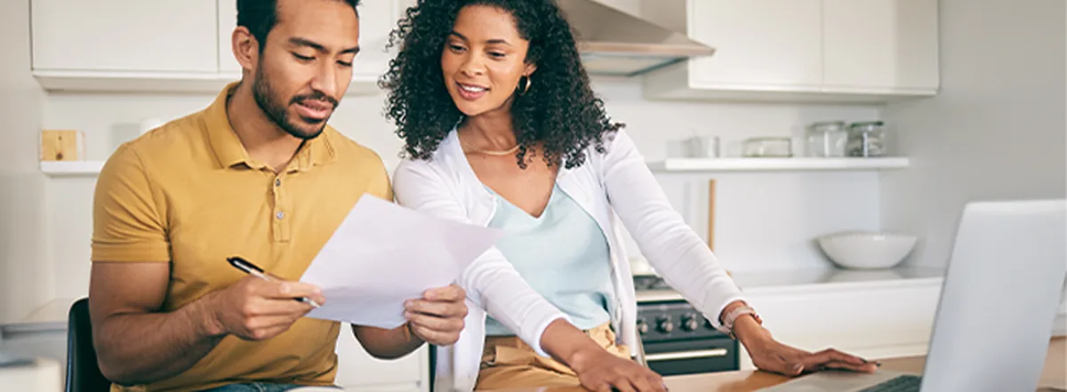 Couple reviewing day-to-day monthly expenses together at kitchen table