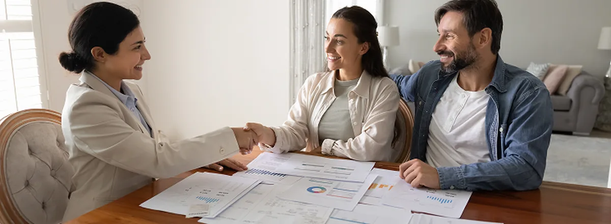Couple shaking hands with financial advisor during meeting