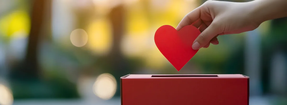 Person putting red heart into red donation box