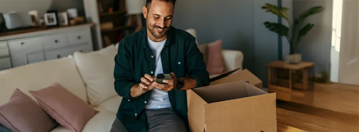 Man sitting on couch making donation to charity on mobile phone