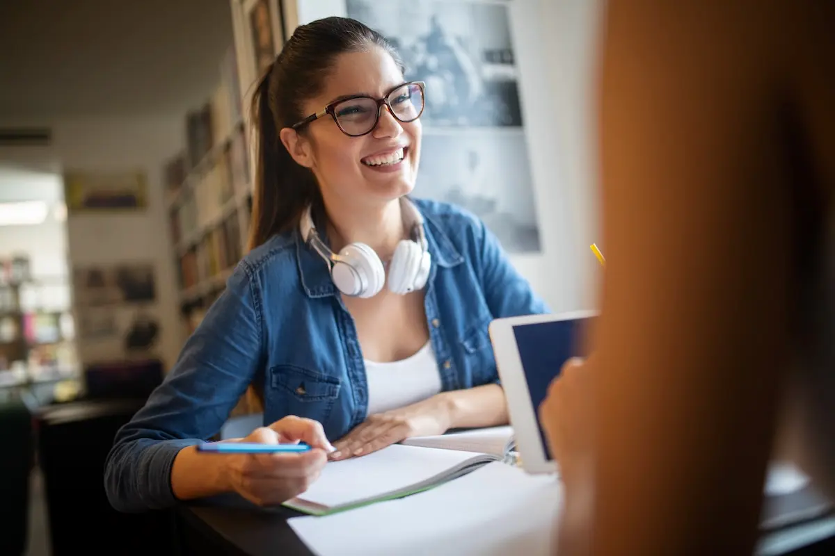 Happy female student studies and talks to a classmate at university.