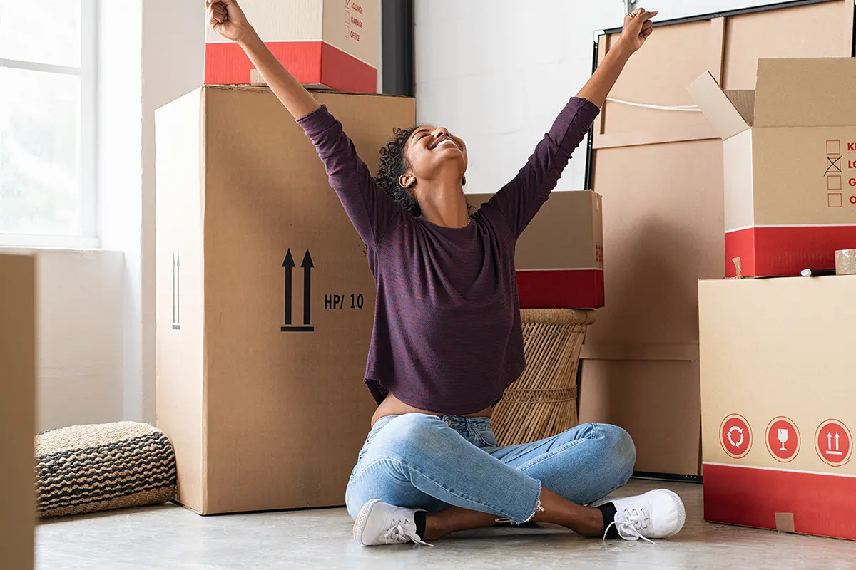 Happy woman celebrating surrounded by moving boxes.