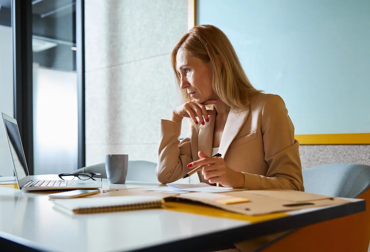 A concentrated woman staring at the laptop screen.