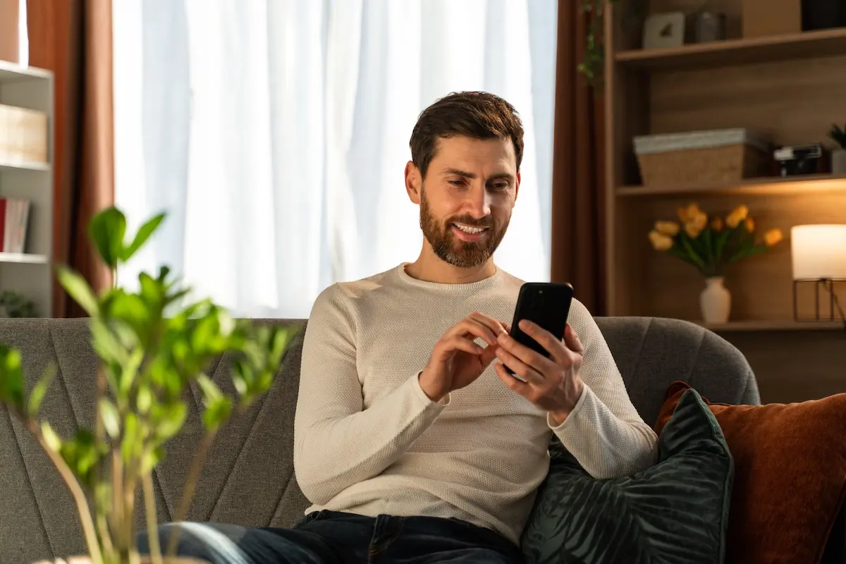 Man relaxing on the couch using a mobile phone.