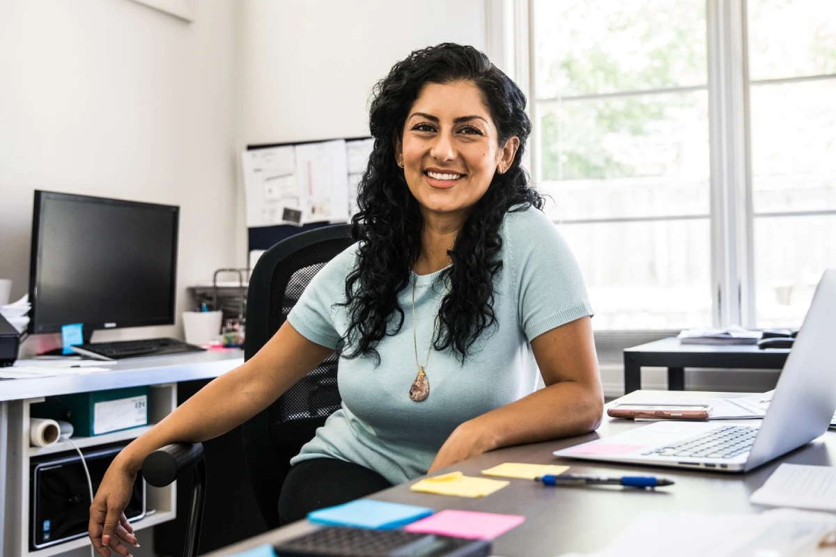 A woman smiling while sitting at the desk.