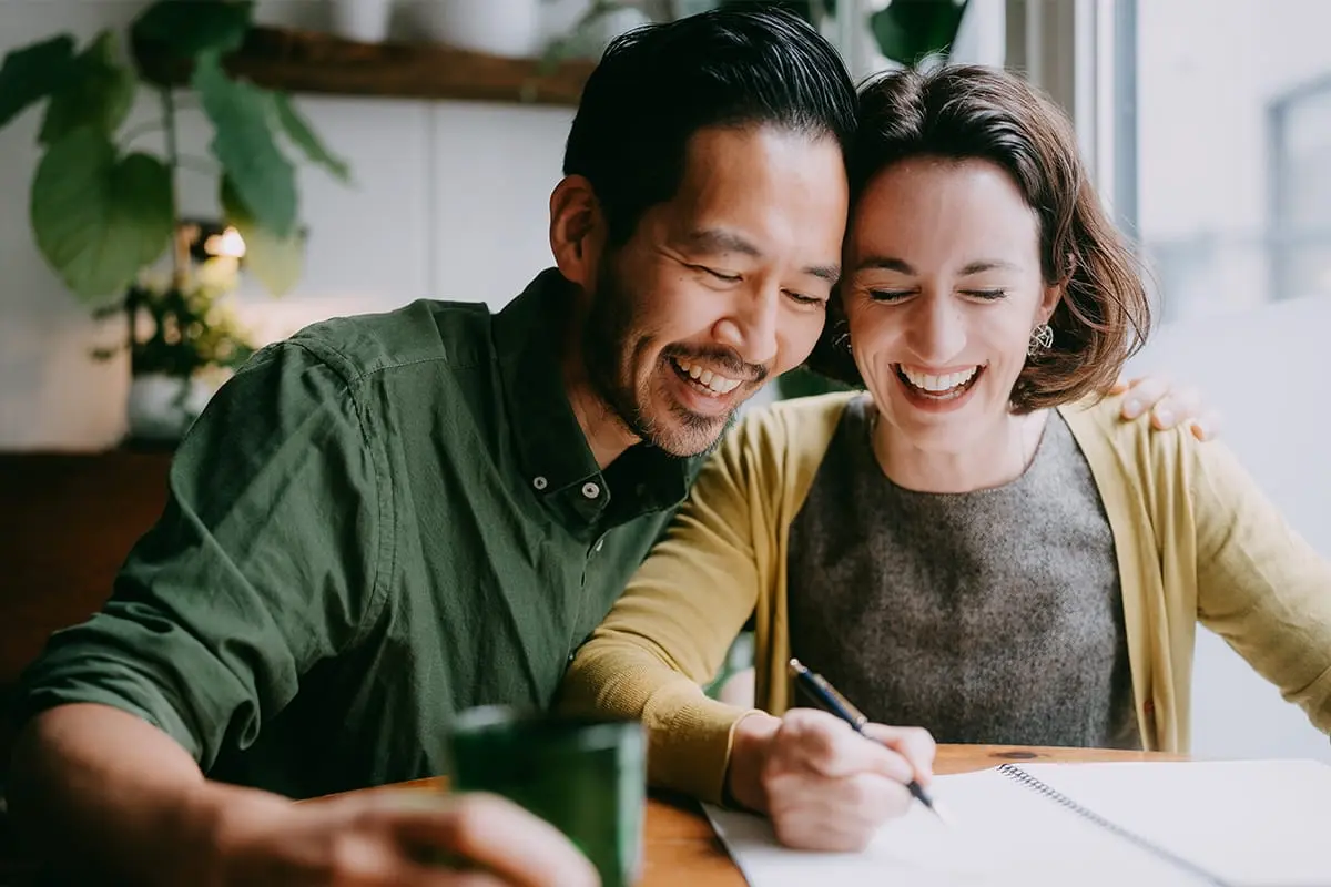 A couple smiling while signing documents.