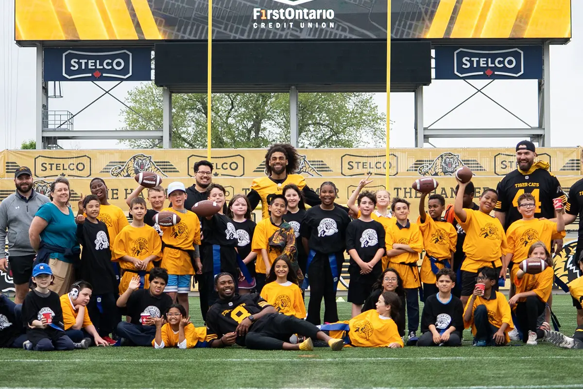 Community football event with players and children posing on a field.