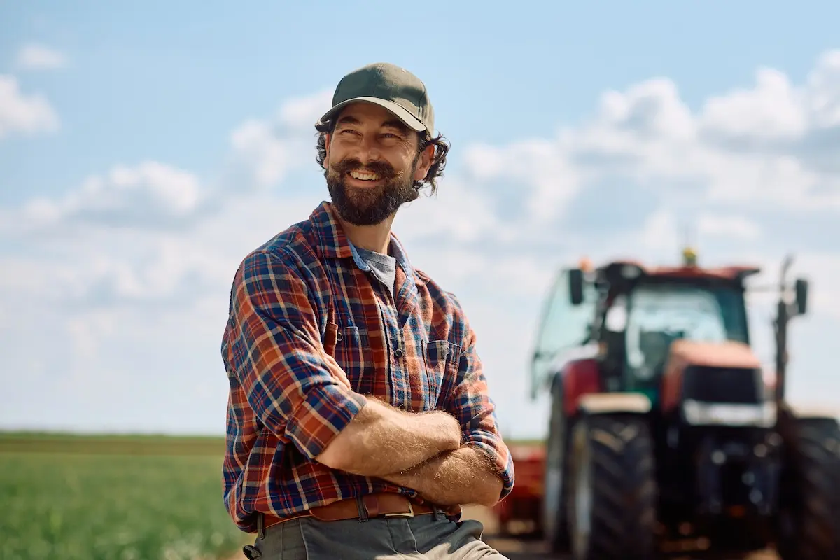 Proud farmer with crossed arms in the field looking away.