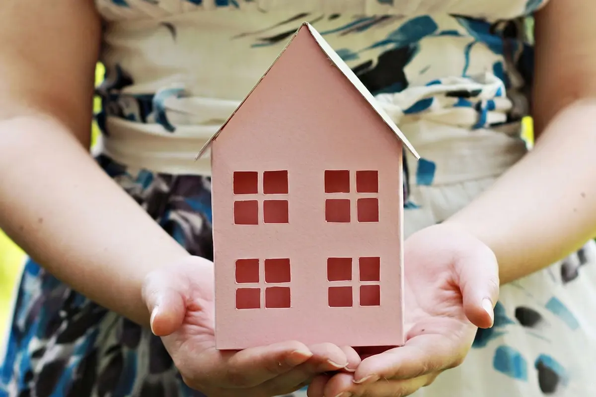 Woman Holding Pink House Made of Craft Paper.
