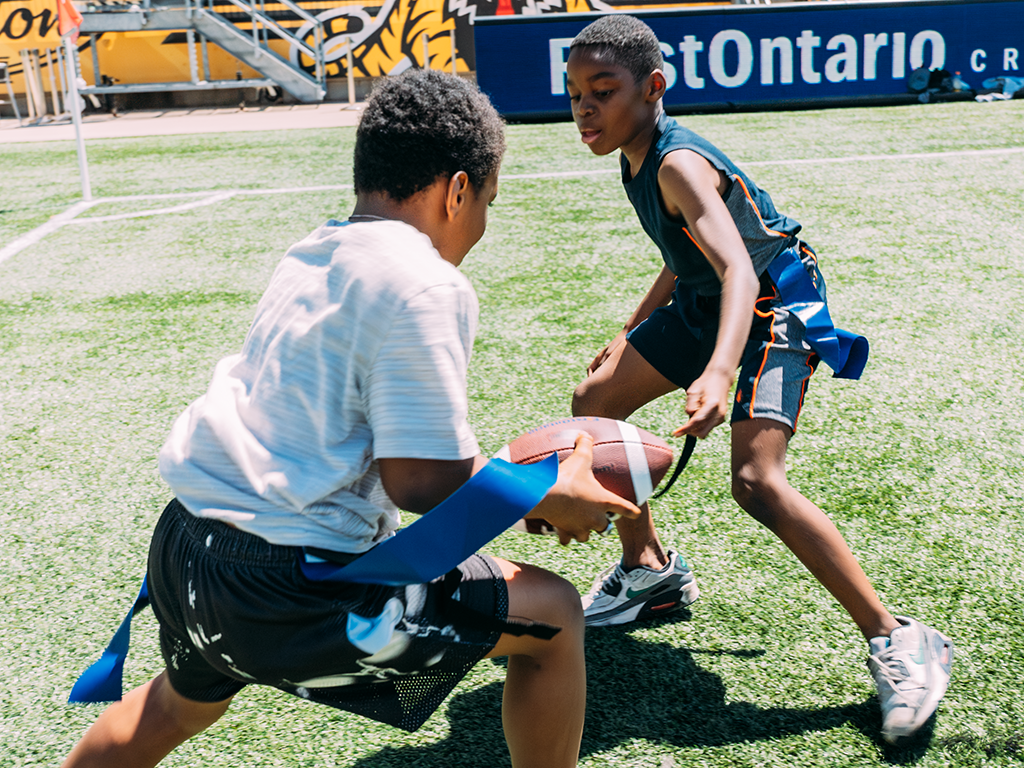 Two young boys playing flag football at Hamilton Stadium.