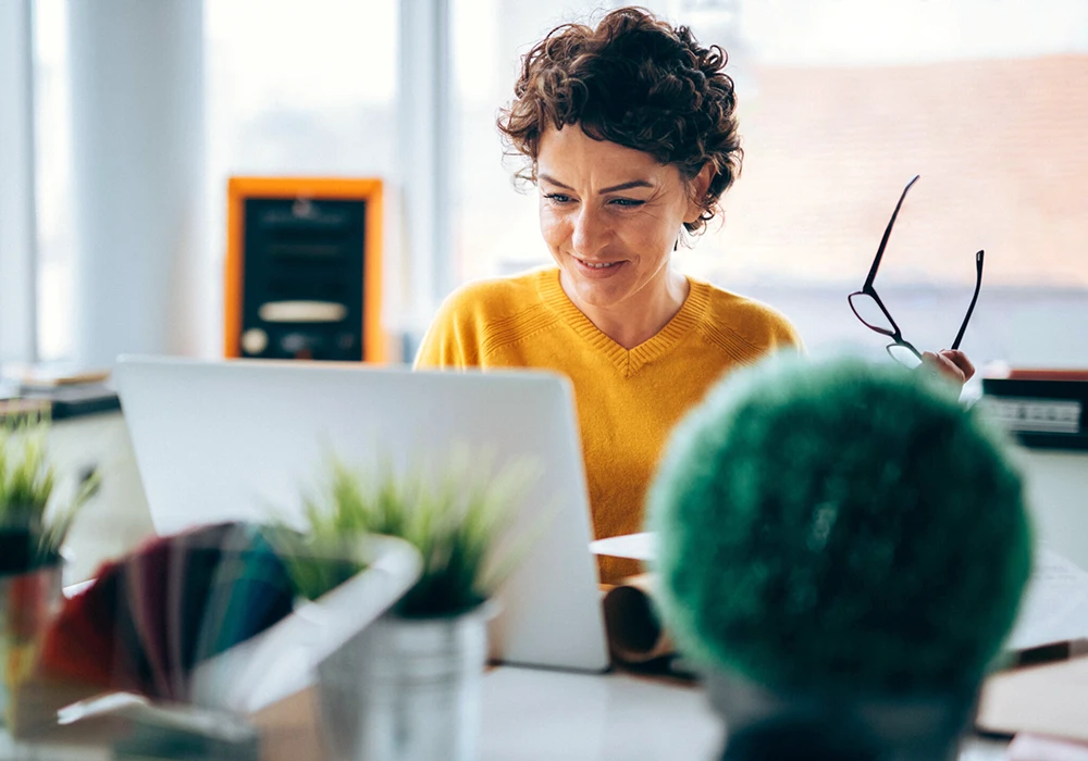 Woman using a laptop at her desk, reviewing information online.