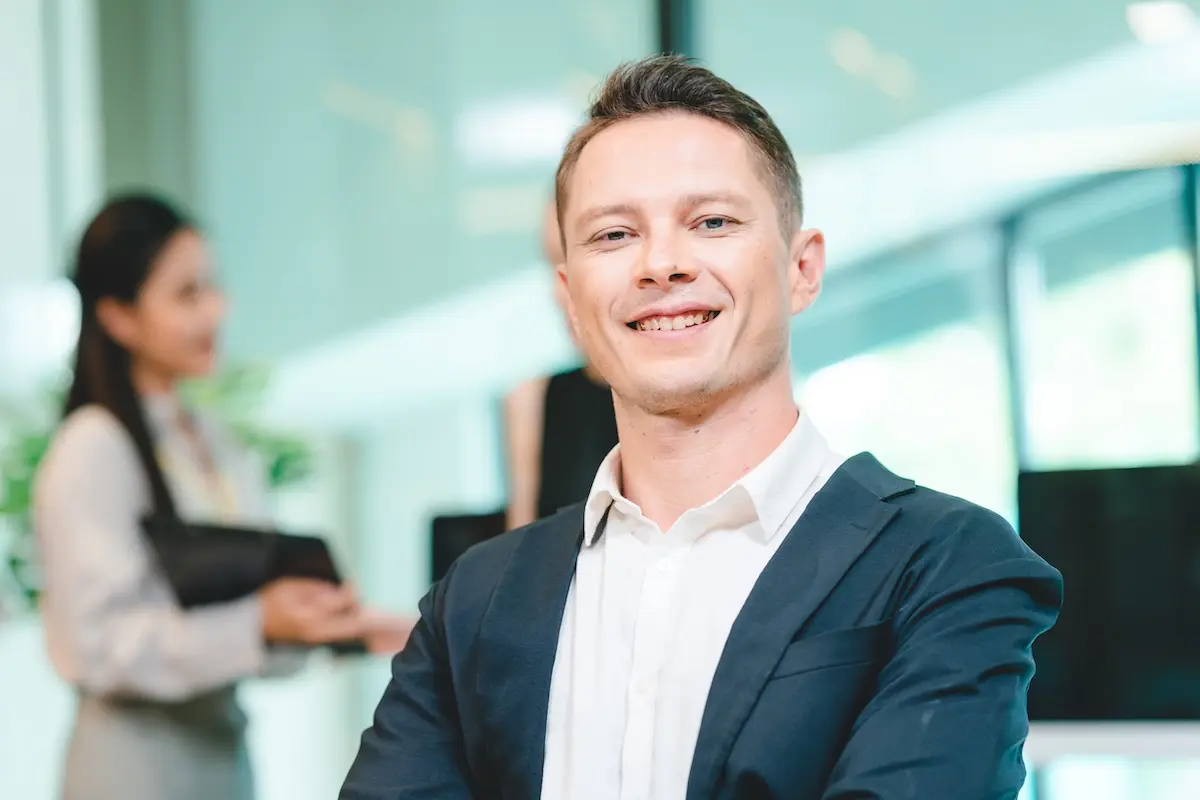 Confident business owner smiles in a modern office environment.