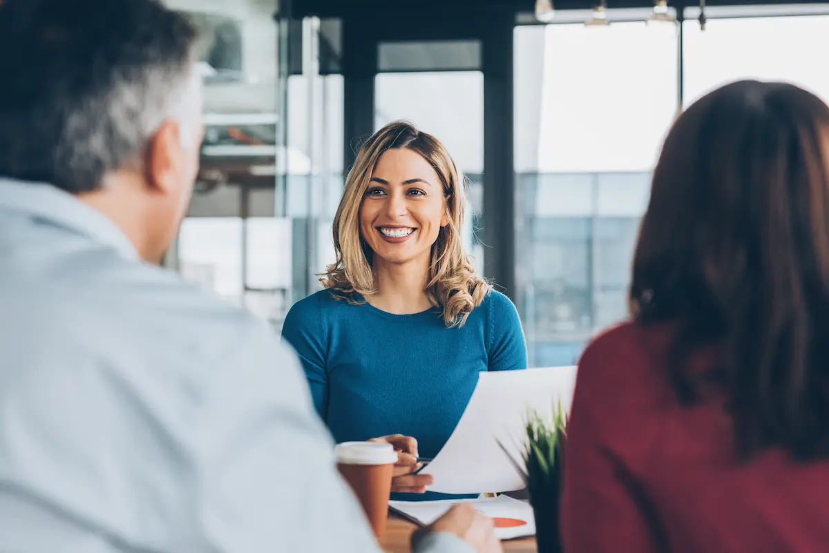 Business professional discussing foreign exchange payments with clients in a modern office setting.
