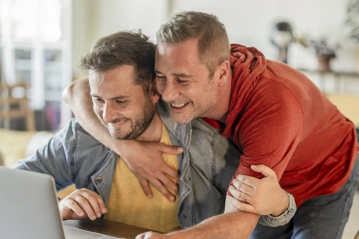 A happy couple using a laptop to explore loan and mortgage insurance options.