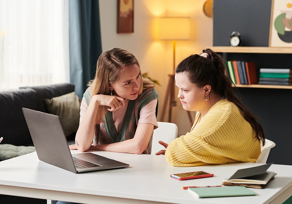 Two individuals working together at a laptop in a supportive environment.