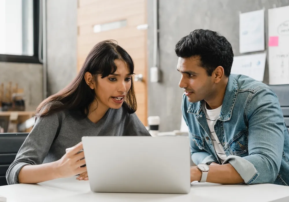 Two people reviewing information together on a laptop, discussing financial details and account terms.
