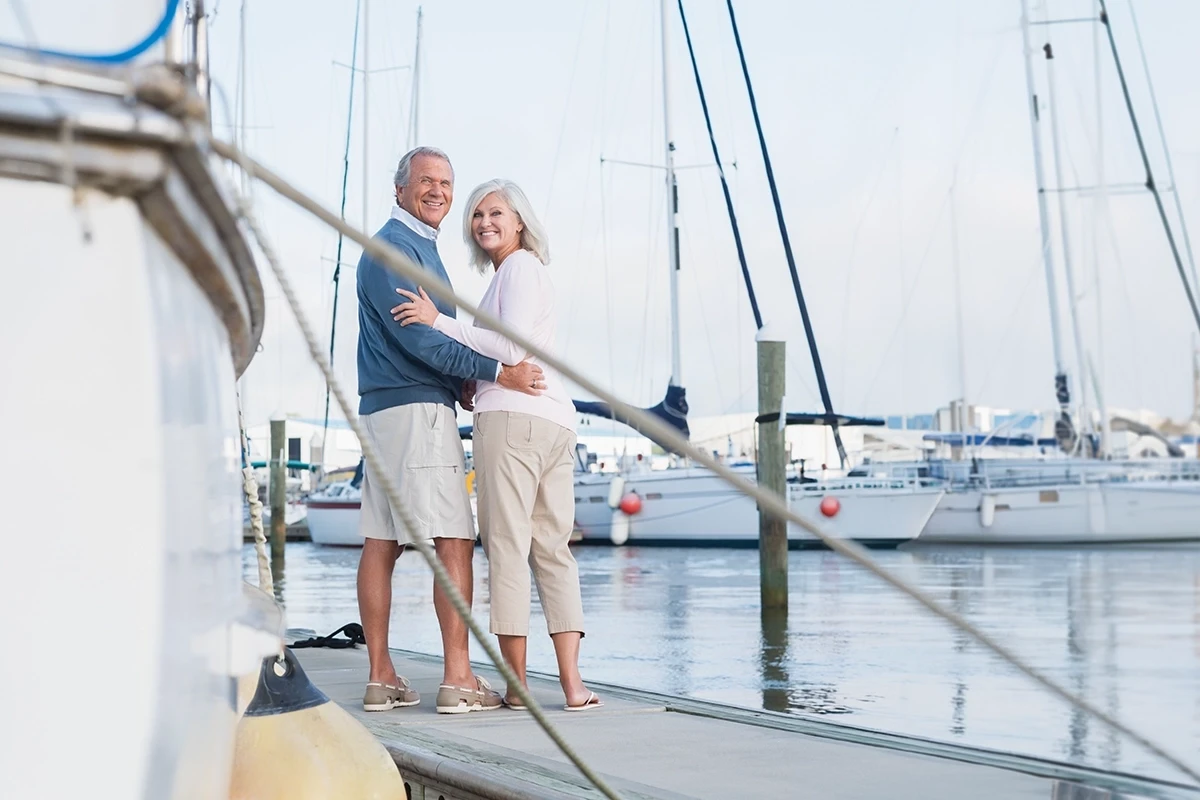 Couple smiling and embracing while standing on dock in a marina